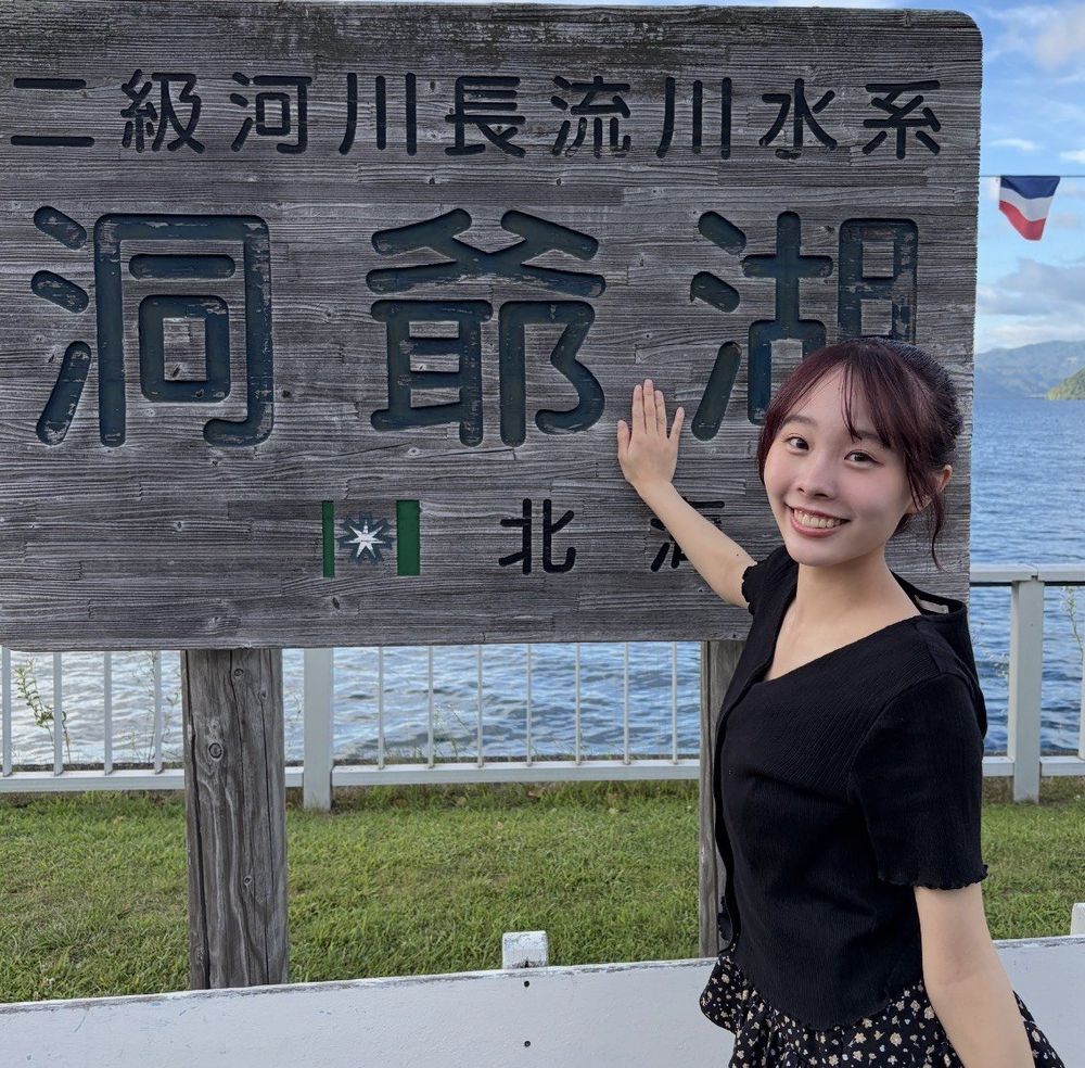洞爺湖の看板に手を添えて笑う叶愛